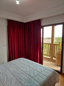 1 dormitorio con cama y cortina roja en Appartement Marrakchia au jardin d'habgour, en Marrakech
