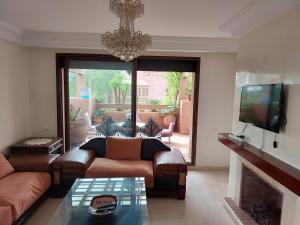 sala de estar con sofá y TV en Appartement Marrakchia au jardin d'habgour, en Marrakech