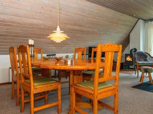 a wooden dining room table with wooden chairs and aandelier at 6 person holiday home in Hvide Sande in Hvide Sande