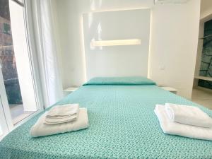 a bedroom with a green bed with towels on it at IL VIAGGIATORE RELAIS SUL MARE in Gaeta
