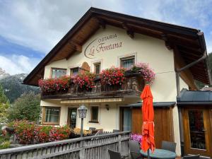 a building with flowers and an umbrella in front of it at Ostaria La Fontana in Corvara in Badia