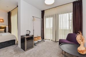 ein Schlafzimmer mit einem Bett, einem lila Stuhl und einem Tisch in der Unterkunft Apartamentai Ešerinėje in Neringa