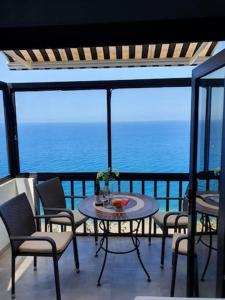 a balcony with a table and chairs and the ocean at Very romantic seaview appartment with warm pool in Patalavaca