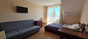 a living room with a bed and a couch at Pokoje i apartamenty "U Beaty" in Karwia