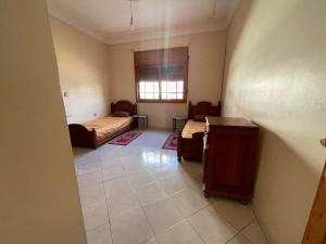 Habitación con 2 camas, mesa y ventana en Dar elward WiFi gratuit, en Kenitra