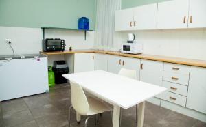 cocina con mesa blanca y nevera blanca en Cozy Blue Guesthouse, en East London