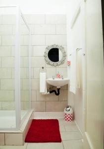 baño con lavabo y ducha con alfombra roja en Cozy Blue Guesthouse, en East London