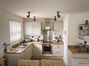 a kitchen with white cabinets and a sink at Beach Boutique in Camber