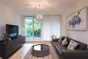 een woonkamer met een bank en een tv bij Chelsea Cascade London Flat in Londen