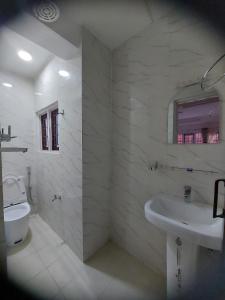 La salle de bains blanche est pourvue d'un lavabo et de toilettes. dans l'établissement Om Bramha Hotel, à Katmandou