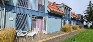 a blue house with two chairs and a table on a deck at Laiko marios in Preila