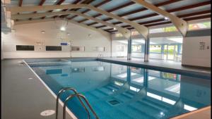 a large swimming pool in a building at Foxes Sea Side Retreat Deluxe Chalet is a lovely holiday home tucked away on the Kent Coast in Kingsdown