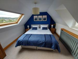 a bedroom with a blue and white bed in a attic at Railway Cottage in Conwy