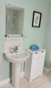 a white bathroom with a sink and a mirror at Railway Cottage in Conwy