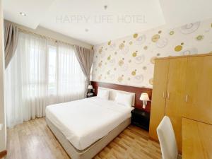 Happy Life Hotel District 7 Gần SECC في مدينة هوشي منه: غرفة نوم بسرير ابيض وفندق حياة سعيدة