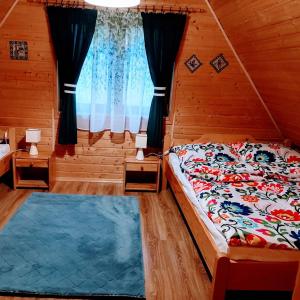 Schlafzimmer mit einem Bett und einem Fenster in der Unterkunft Domki Obertyny in Wetlina