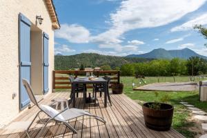 una terrazza in legno con tavolo e sedie. di Plaines-Provence Spa&Sauna a Digne-Les-Bains