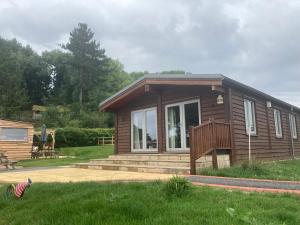 a small cabin with a porch and a deck at Stag Lodge School House Farm in Leighton