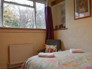 a bedroom with a bed and a window and a chair at Beck Cottage in Ambleside