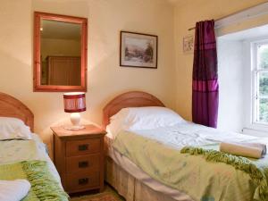 a bedroom with two twin beds and a mirror at Beck Cottage in Ambleside