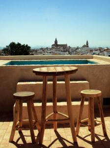 d'une table en bois et de deux tabourets sur un balcon. dans l'établissement LA POSADA DEL LIMONERO, à Fuentes de Andalucía