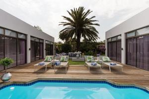 uma villa com uma piscina e um pátio em OCEAN BREEZE SUNSET BEACH - Cape Town em Cidade do Cabo