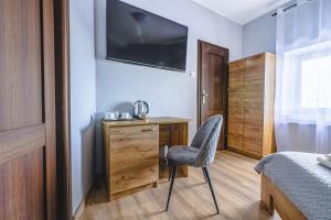 a bedroom with a chair and a desk with a television at Royal Gdansk in Gdańsk