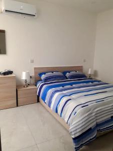 a bedroom with a large bed with blue and white sheets at Panoramic Penthouse Haven in Mellieħa