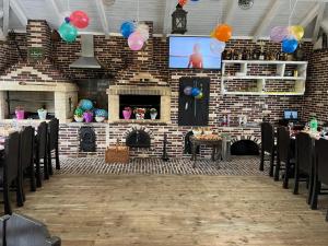 a room with a brick wall with tables and balloons at LA RĂSCRUCE DE APE in Suceviţa
