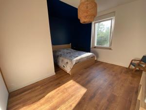 a bedroom with a bed with a blue wall and a window at Maison de ville au bord de l’eau (3) in Saint-Nicolas-de-Port