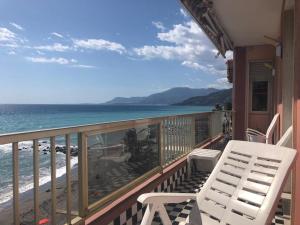 un balcón con una silla blanca y el océano en Suite, en Ventimiglia