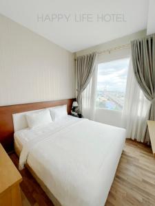 Un dormitorio con una gran cama blanca y una ventana en Happy Life Hotel District 7 Gần SECC, en Ho Chi Minh