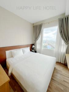 a bedroom with a large white bed and a window at Happy Life Hotel District 7 Gần SECC in Ho Chi Minh City