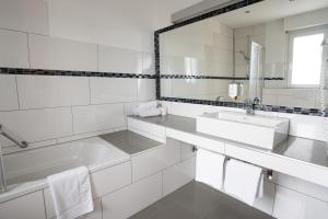 a white bathroom with a sink and a mirror at Europa Kehl Hotel in Kehl am Rhein