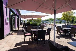 un patio al aire libre con mesas, sillas y sombrillas en Europa Kehl Hotel, en Kehl am Rhein