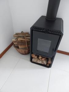 a black stove with a basket of logs at Lumiar Eco Lodge - Chalé Telhado Verde in Nova Friburgo