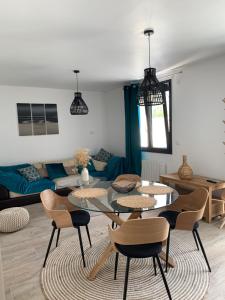 a living room with a table and chairs and a couch at La maison de la vallée in Ranville