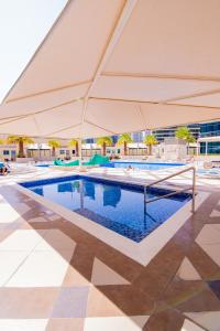 a swimming pool with a large white umbrella at Full Apartment in Dubai Marina,80m from beach in Dubai
