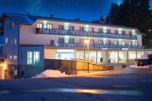 un grand bâtiment avec des lumières sur son côté dans l'établissement Hotel Polsa, à Brentonico