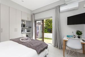 Un dormitorio con una cama y un escritorio y una ventana. en OCEAN BREEZE SUNSET BEACH - Cape Town, en Ciudad del Cabo