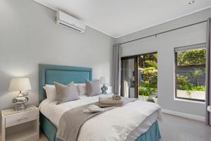um quarto com uma cama grande e uma cabeceira azul em OCEAN BREEZE SUNSET BEACH - Cape Town em Cidade do Cabo