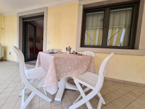 a table with white chairs and a pink table cloth at STELLA MARINA centralissimo bilocale con grande terrazzo in Grado