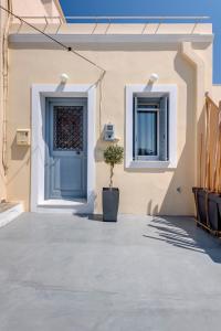 a house with a blue door and a potted plant at Cova Philoxenia House in Ermoupoli