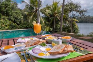 una mesa de desayuno con huevos, tostadas y un vaso de zumo de naranja. en Serendipity Lake - Hikkaduwa en Hikkaduwa