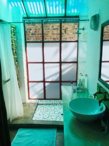 łazienka z zieloną umywalką i oknem w obiekcie (Sub)urban retreat w mieście Johannesburg