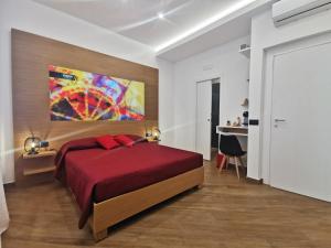 a bedroom with a red bed and a painting on the wall at Maqueda Mood in Palermo