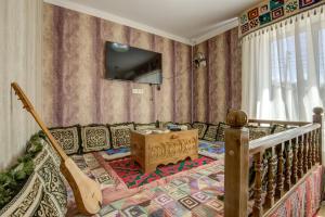 a living room with a couch and a tv on a wall at Ordo Hotel in Karakol
