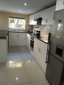 a kitchen with white cabinets and a refrigerator at On the Wrench in Cape Town
