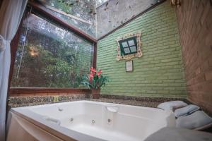 a bath tub in a bathroom with a window at Urikana Boutique Hotel in Teresópolis