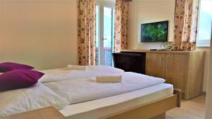 1 dormitorio con cama con sábanas blancas y almohadas moradas en Hotel Krone en Morter
